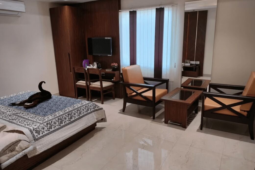 Une chambre d’hôtel avec un lit, un bureau, une télévision, une chaise et un canapé.