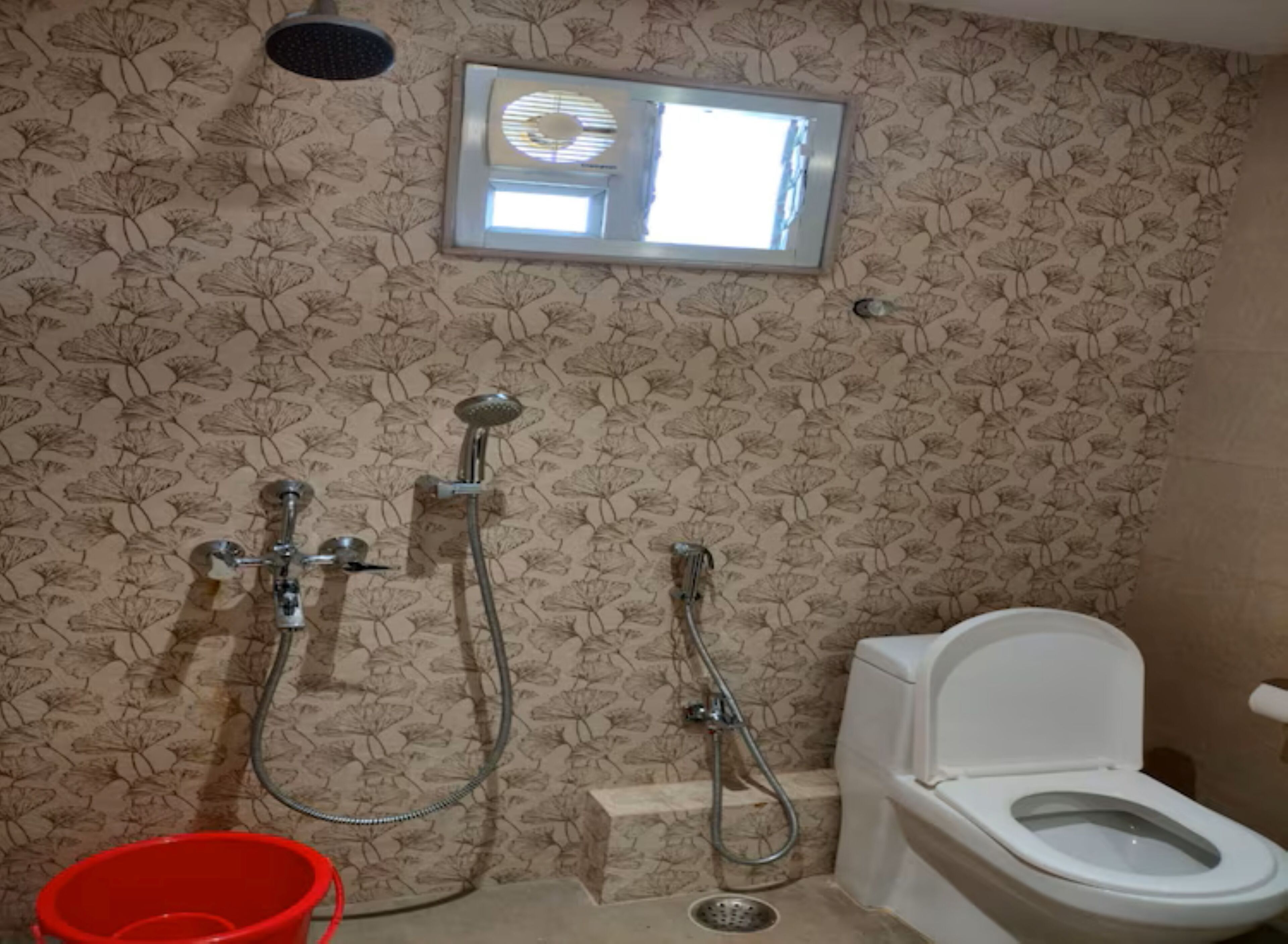 Een badkamer met douche, toilet en een raam met zonwering.