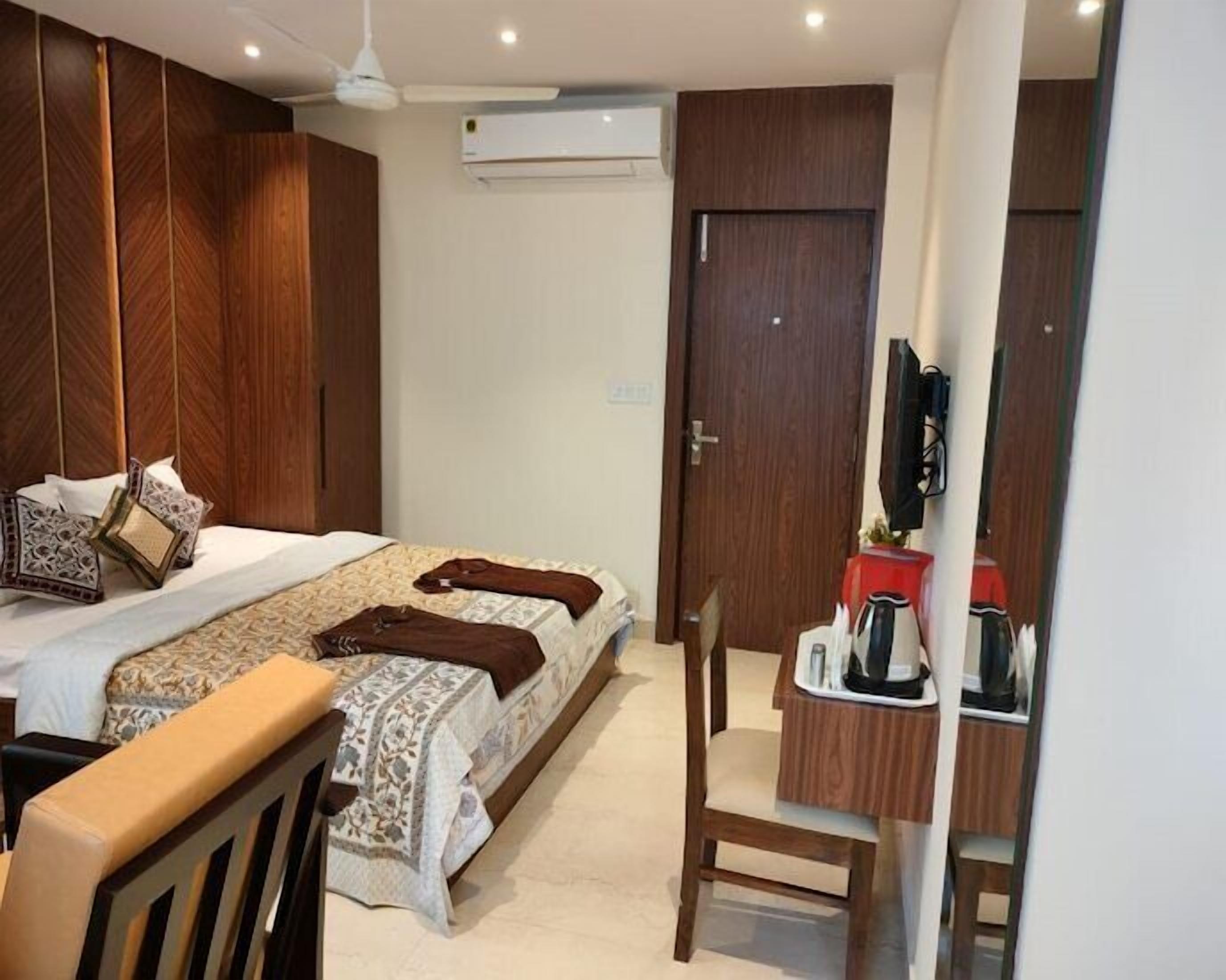 Une chambre à coucher comprenant un lit, une table de chevet, une chaise et un téléviseur fixé au mur.
