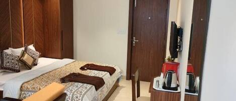 A bedroom with a bed, bedside table, chair, and a TV mounted on the wall.