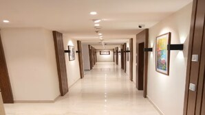 A hotel corridor with a polished floor, wooden paneling, and framed artwork on the walls. - Eennra Maanikko (Krishnanagar)
