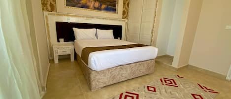 A bedroom with a bed, bedside table, and a painting on the wall.