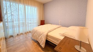 A bedroom with a bed, a bedside table, a lamp, and a window with curtains. - Beautiful apartment with pets allowed in Évian (Évian-les-Bains)