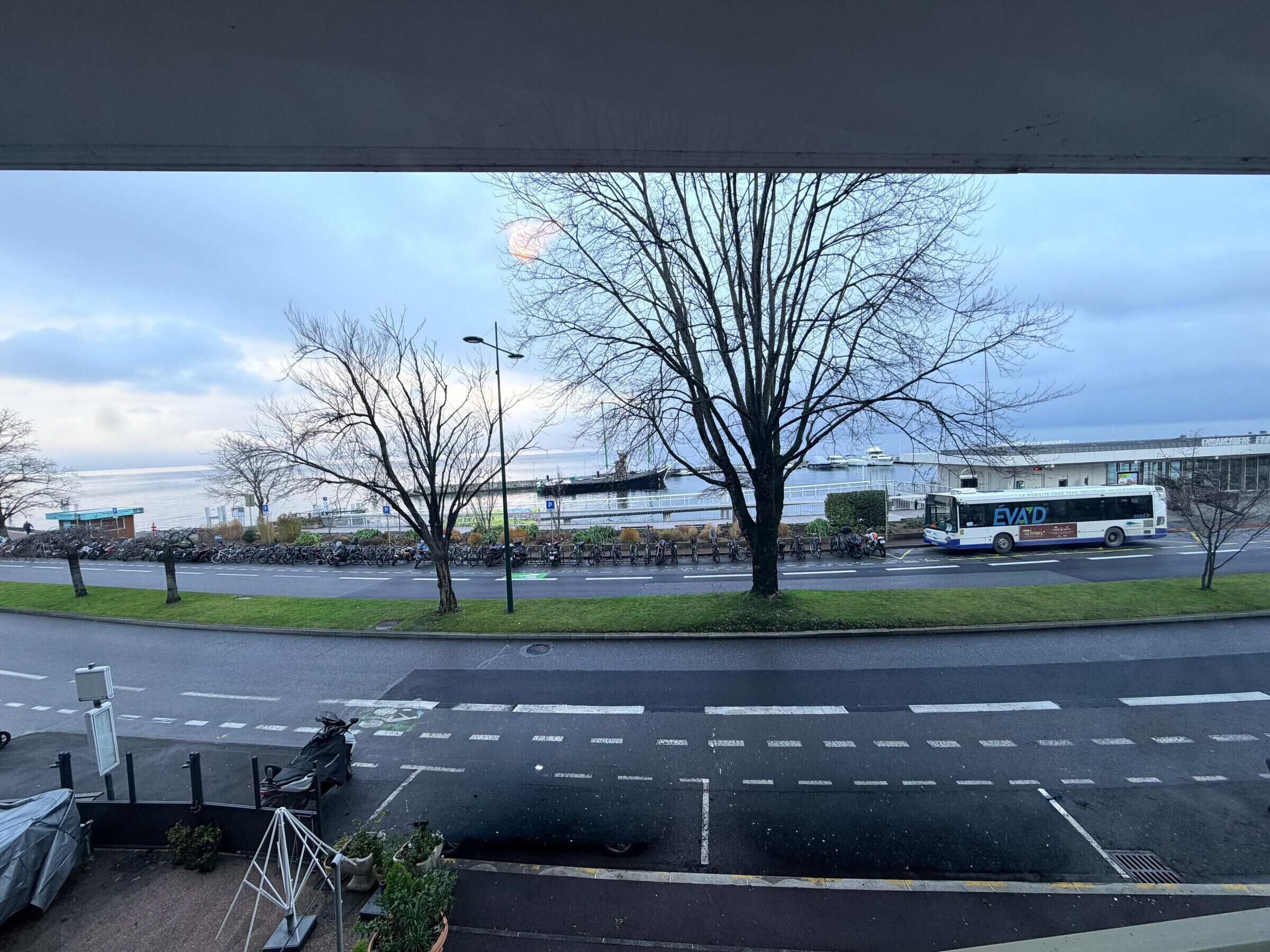 A parking lot with a bus, trees, and a building in the background.