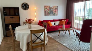 A living room with a red sofa, a round table, a dining table with chairs, a wall clock, and a painting. - Beautiful apartment with pets allowed in Évian (Évian-les-Bains)