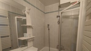 Une salle de bain équipée d’une baignoire, d’une douche, d’un lavabo et d’un miroir.