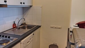 Une cuisine de taille réduite, équipée d’un évier, d’une cuisinière et d’un lave-vaisselle.