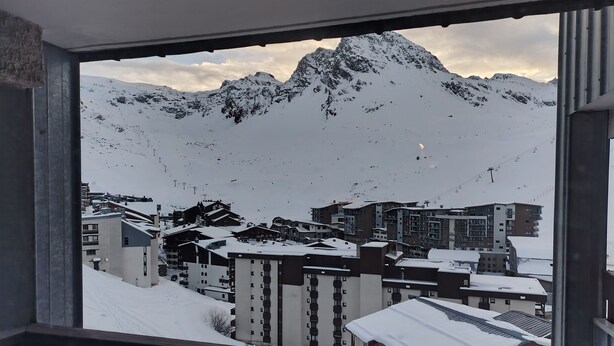 Une vue sur une chaîne de montagnes enneigées, avec une ville située en contrebas.