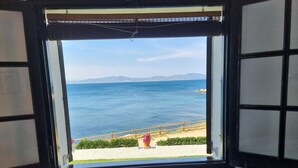 Una ventana con vista al mar, baranda de madera y una planta en maceta.