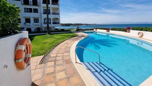 Una piscina con agua cristalina azul, rodeada por un solárium con baldosas y un flotador en la pared.