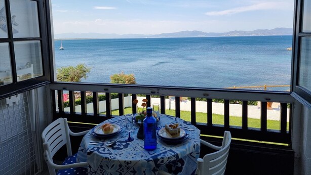 Un comedor con una mesa dispuesta para dos personas, con vistas a un cuerpo de agua y montañas al lejano.