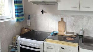 Eine Küche mit Gasherd, Backofen, Mikrowelle und einer kleinen Spüle.