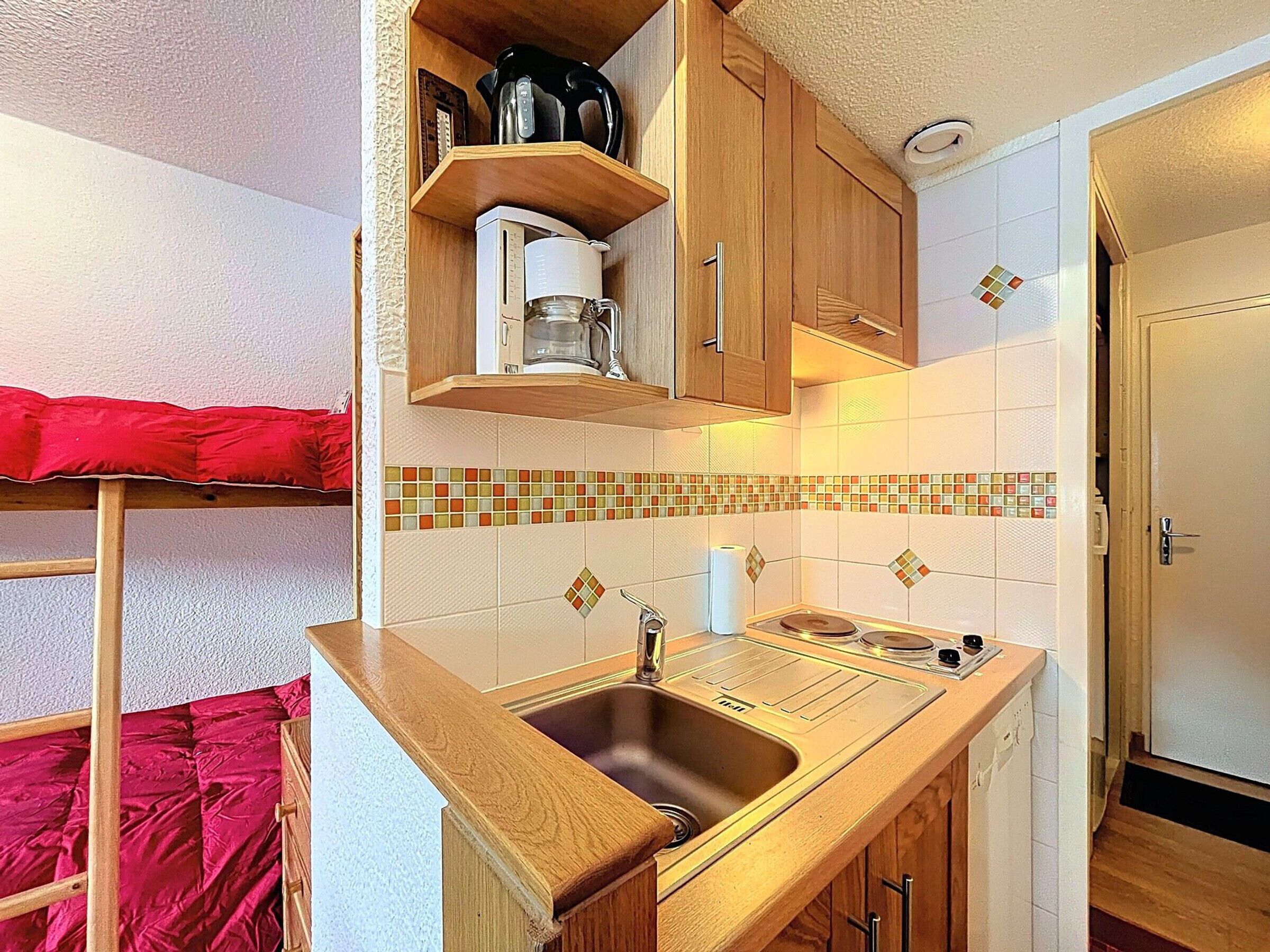 Une cuisine de taille réduite, avec des meubles de rangement en bois, un évier et une machine à café.