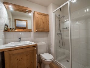 Un bagno con un mobile bagno in legno, un water, una cabina doccia in vetro e uno specchio sopra il mobile.