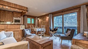 Une chambre confortable, aménagée dans le style d’un chalet, avec des murs en bois, un coin repas et une grande fenêtre donnant sur le paysage extérieur.