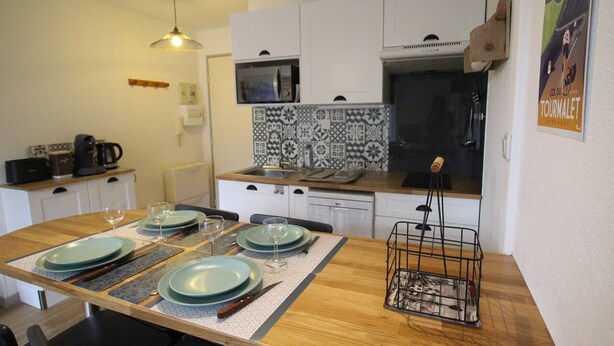 A compact kitchen with white cabinets, a microwave, and a tiled backsplash. - Cozy apartment in Luchon, 4 ppl, near spa, with parking (Bagnères-de-Luchon)
