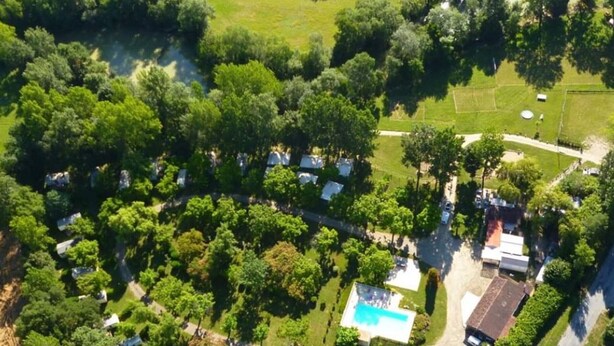 Vista aérea de un camping con vehículos recreativos, piscina y un edificio grande.