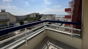A balcony with a view of a coastal area, including buildings and a road with parked cars. - 3-Bedroom Apt near beach, with garage (Cucq-Stella Plage)
