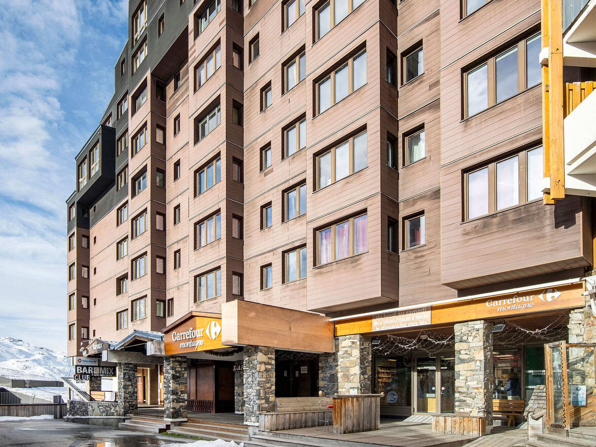 A multi-story hotel with a stone facade, a bar, and a restaurant named "Carrefour Montagne".