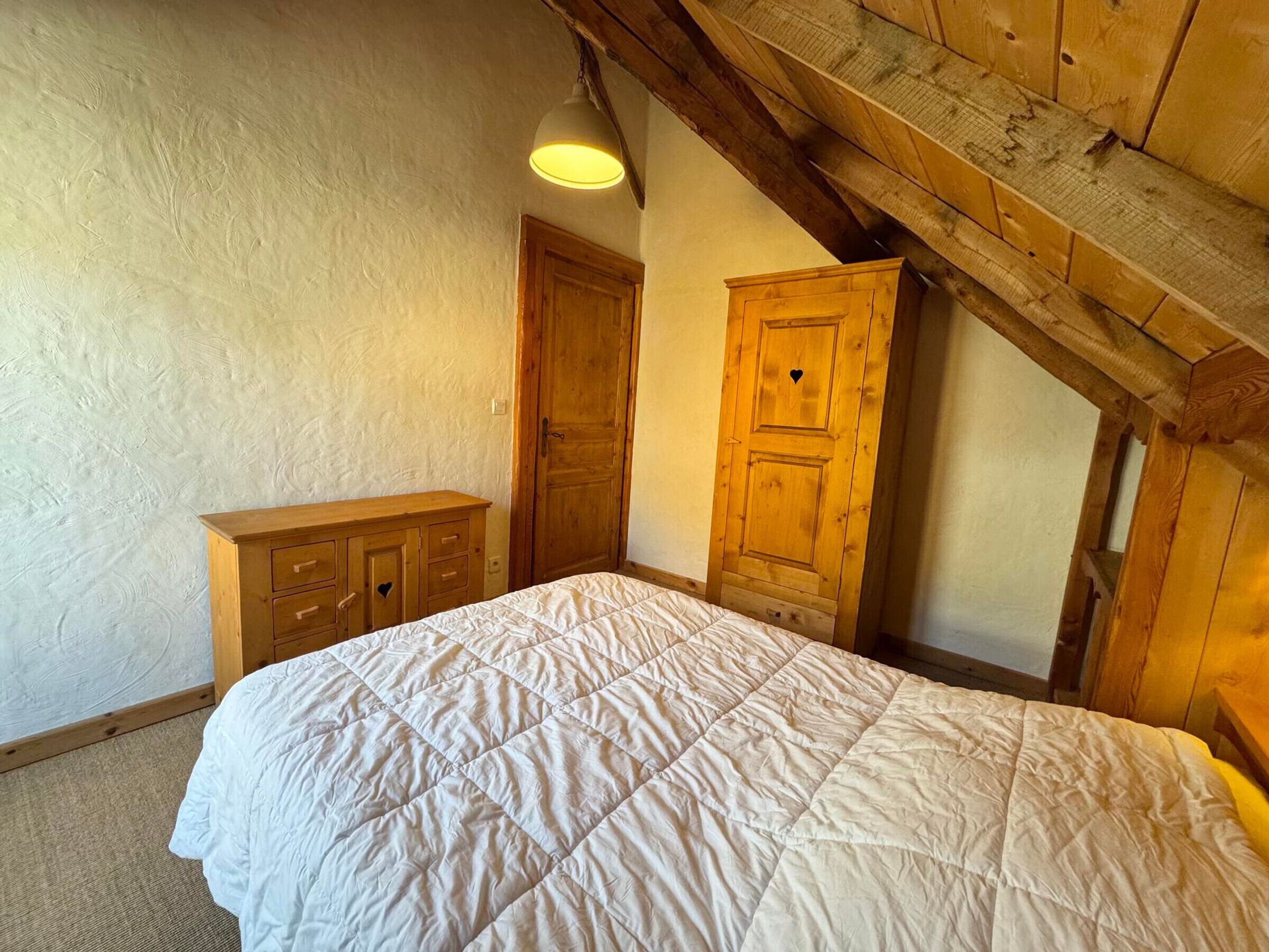 Un dormitorio con una cama, un aparador y un armario de madera.
