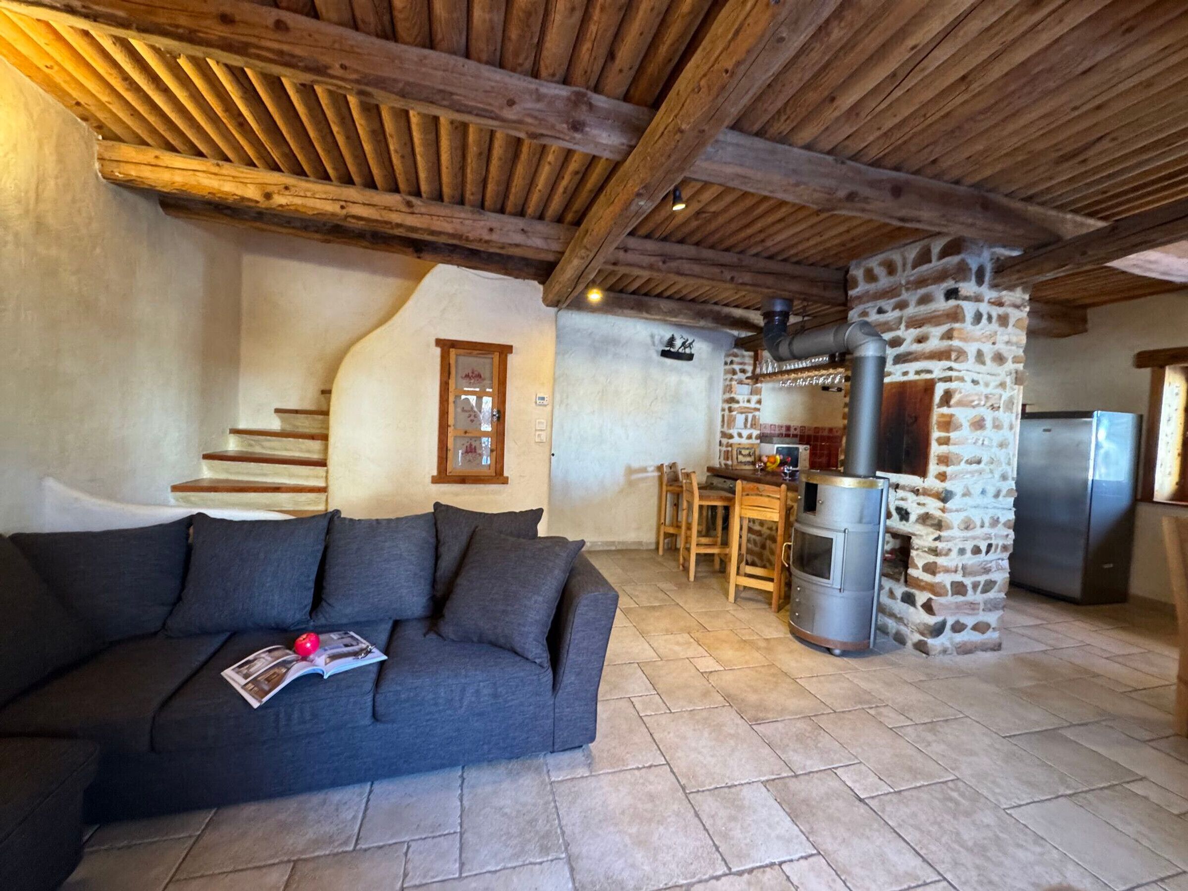 Ein gemütlicher Wohnbereich mit einer Couch, einem Kamin aus Stein und einer Küche mit Kühlschrank.
