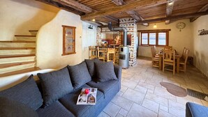 Un salon chaleureux avec un plafond en bois, une cheminée en pierre et un coin repas doté de meubles en bois.