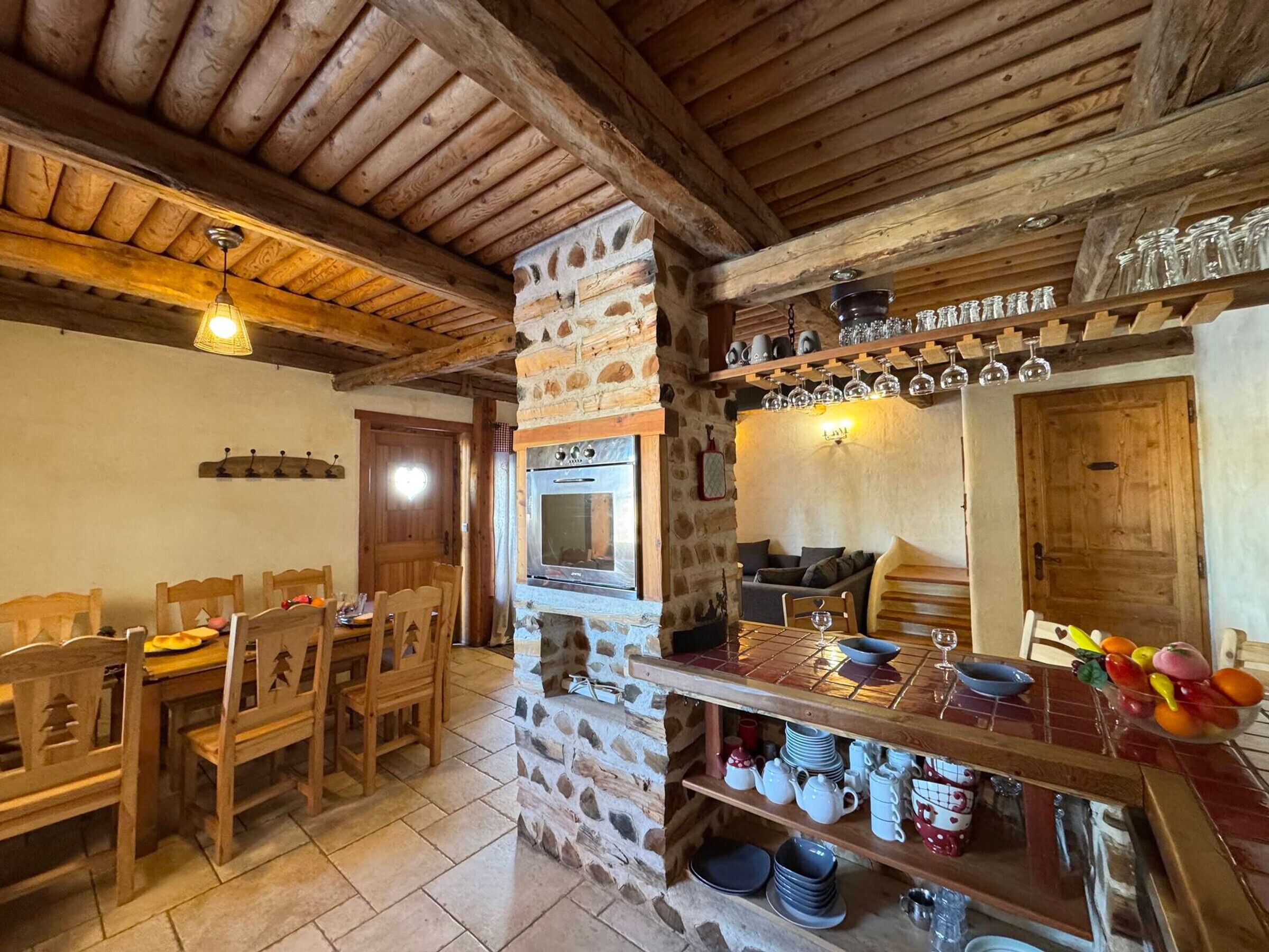 A rustic dining area with wooden furniture, a stone wall, and a built-in oven.