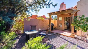 Un patio con mesa y sillas, una parrilla y una pérgola.