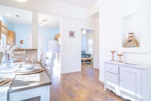 Eine geräumige Küche mit Holzboden, weißen Schränken und einem Essbereich mit Tisch für vier Personen.