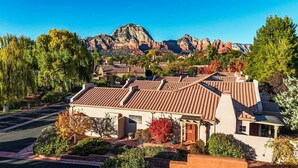 Zona residencial con casas de techos rojos, rodeada de árboles y montañas al fondo.