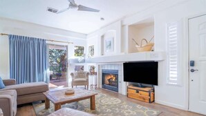 Una sala de estar con sofá, mesa de centro, televisor, chimenea y una puerta.