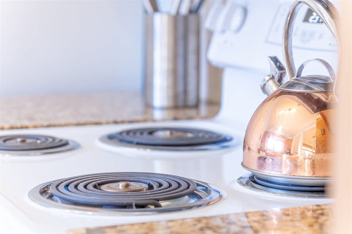 Una cocina con cuatro hornillas de gas y un hervidor sobre la estufa.