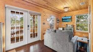 Ein Holzblockhaus mit einer Couch, einem Fernseher und einer Essecke.