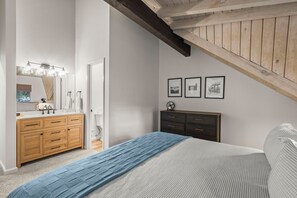 A bedroom with a bed, a wooden dresser, a vanity with a mirror, and framed pictures on the wall. - 63 Creekside West | 3BR/2.5BA Incline Village, MTN (Incline Village)
