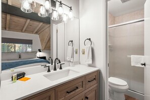 A modern bathroom with a large mirror, a sink with a faucet, a toilet, and a shower area. - 63 Creekside West | 3BR/2.5BA Incline Village, MTN (Incline Village)