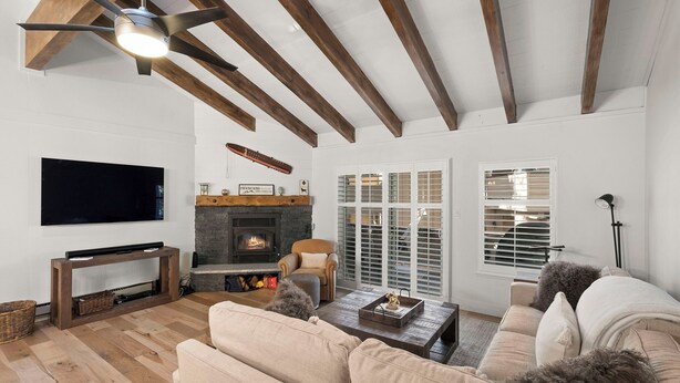 A living room with a fireplace, wooden beams, a television, and a sofa. - 3BR/2.5BA Incline Village condo, pool, fireplace (Incline Village)