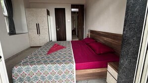 Un dormitorio con cama, mesita de noche, armario y una puerta que da a otra habitación.