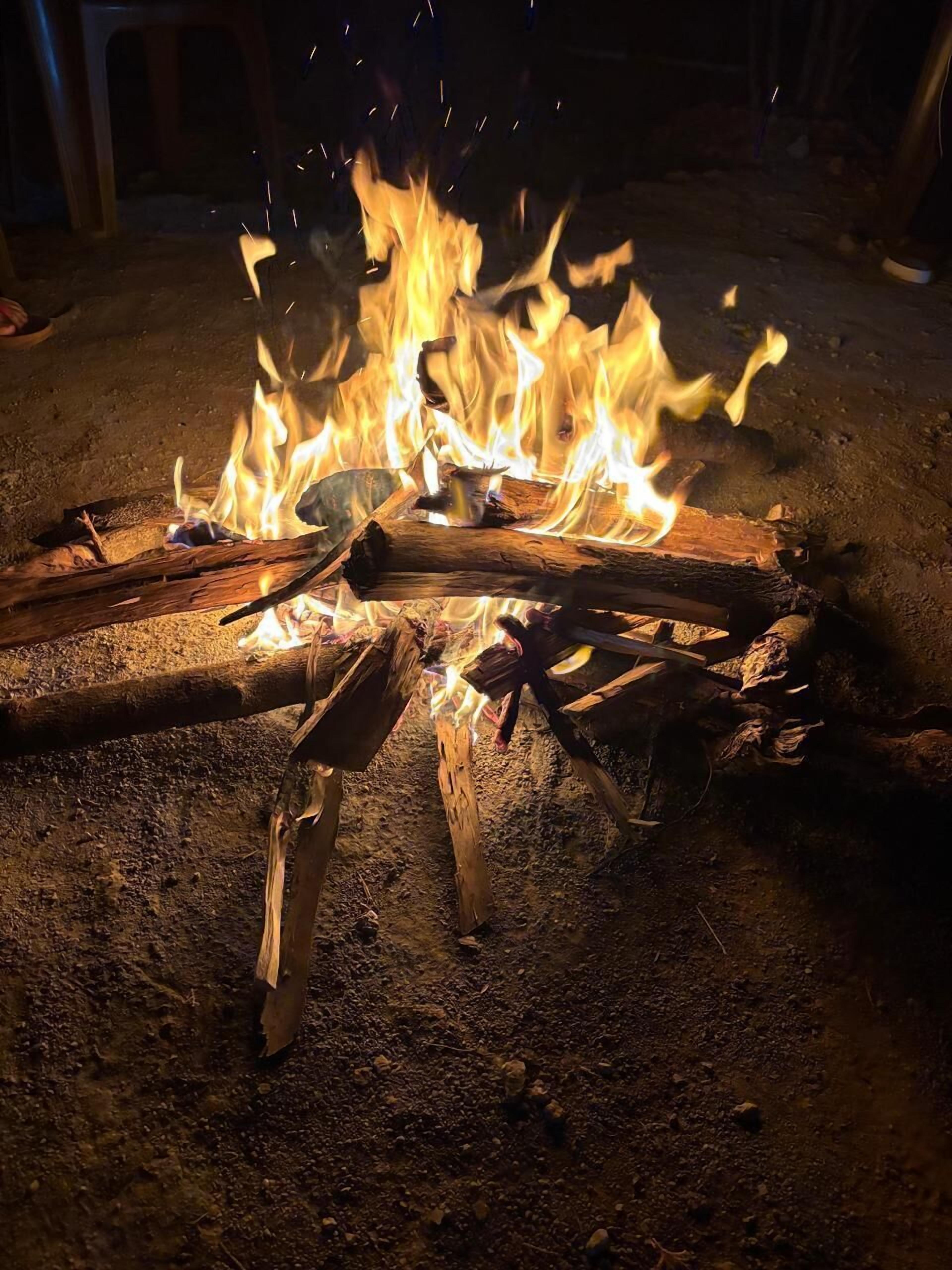 Een kampvuur met blokken hout en gloeiende kolen.