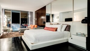 A modern hotel room with a large bed, a seating area with a view, and a glass door leading to a balcony. - Studio • No Resort Fee • Free Parking • XR35 (Las Vegas)