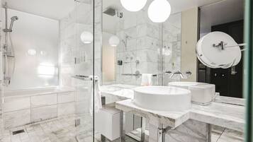 Une salle de bain moderne dotée d’une douche à parois de verre, de deux lavabos et d’un grand miroir.