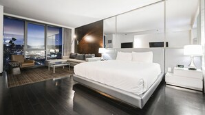 Una habitación de hotel moderna con una cama grande, un sofá, una mesa de centro y un escritorio con una lámpara.