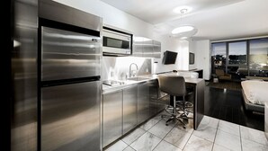 Una cocina moderna con electrodomésticos de acero inoxidable, una zona de bar con asientos y vistas a la ciudad a través de amplios ventanales.