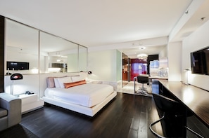 A modern hotel room with a large bed, a desk with a chair, a TV, and a mirror. - SVS: High Floor Mountain View Studio | Open Balcony | Palms Place (Las Vegas)
