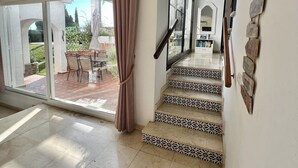 A spacious room with a large sliding glass door leading to an outdoor patio, a staircase with patterned steps, and a wall-mounted light fixture. - 18 - Villa 1km from the beach in Calahonda/Mijas (Mijas Costa)