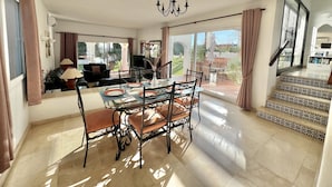 A dining area with a glass table, chairs, and a chandelier. There is a staircase with patterned steps leading to an upper level. - 18 - Villa 1km from the beach in Calahonda/Mijas (Mijas Costa)