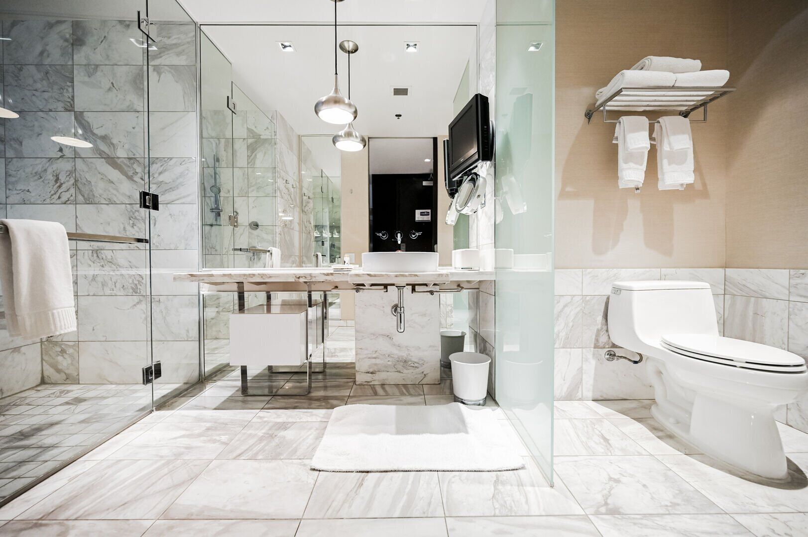 A modern bathroom with a glass-enclosed shower, a large vanity with a mirror, and a toilet.