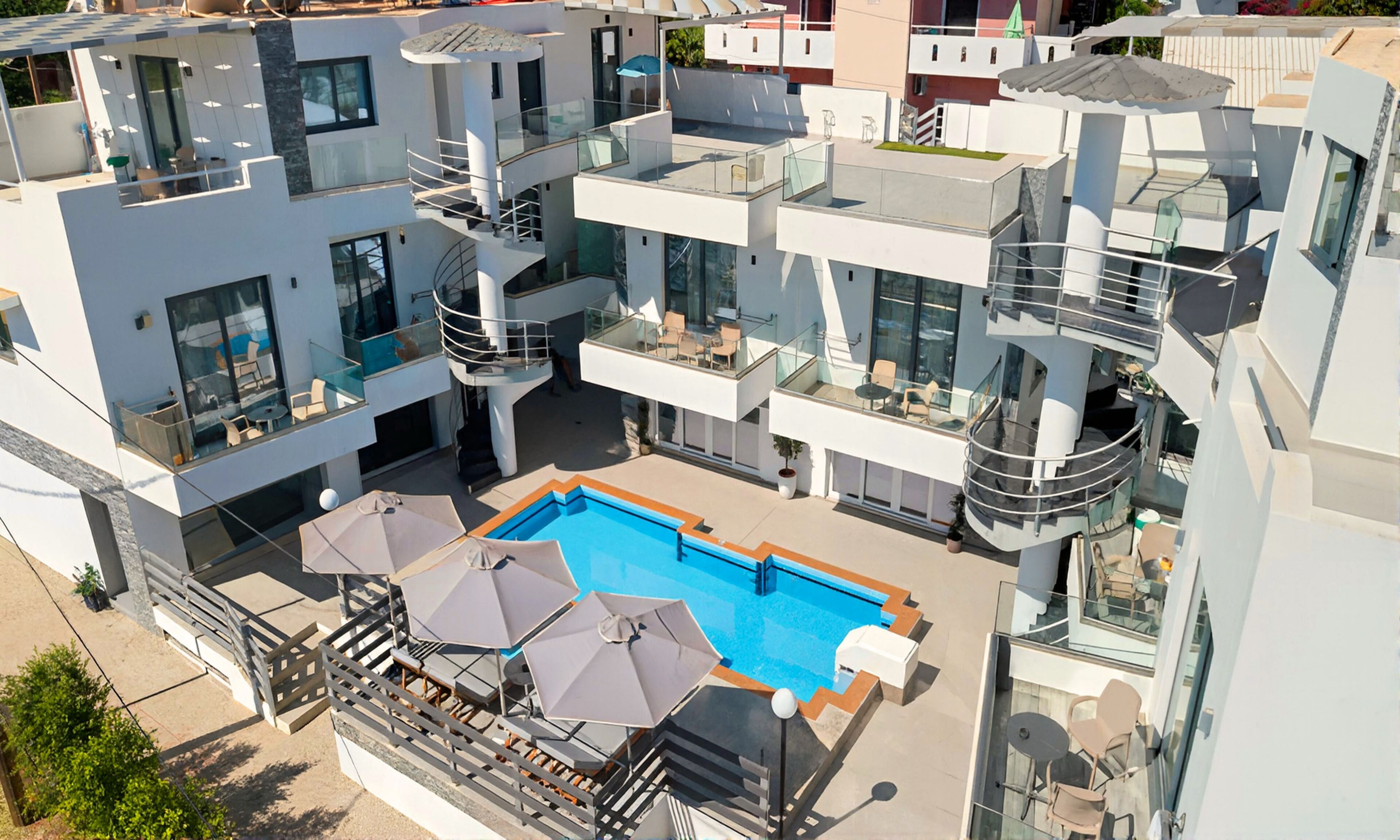 A modern multi-story building with a rooftop pool area, glass railings, and outdoor seating.
