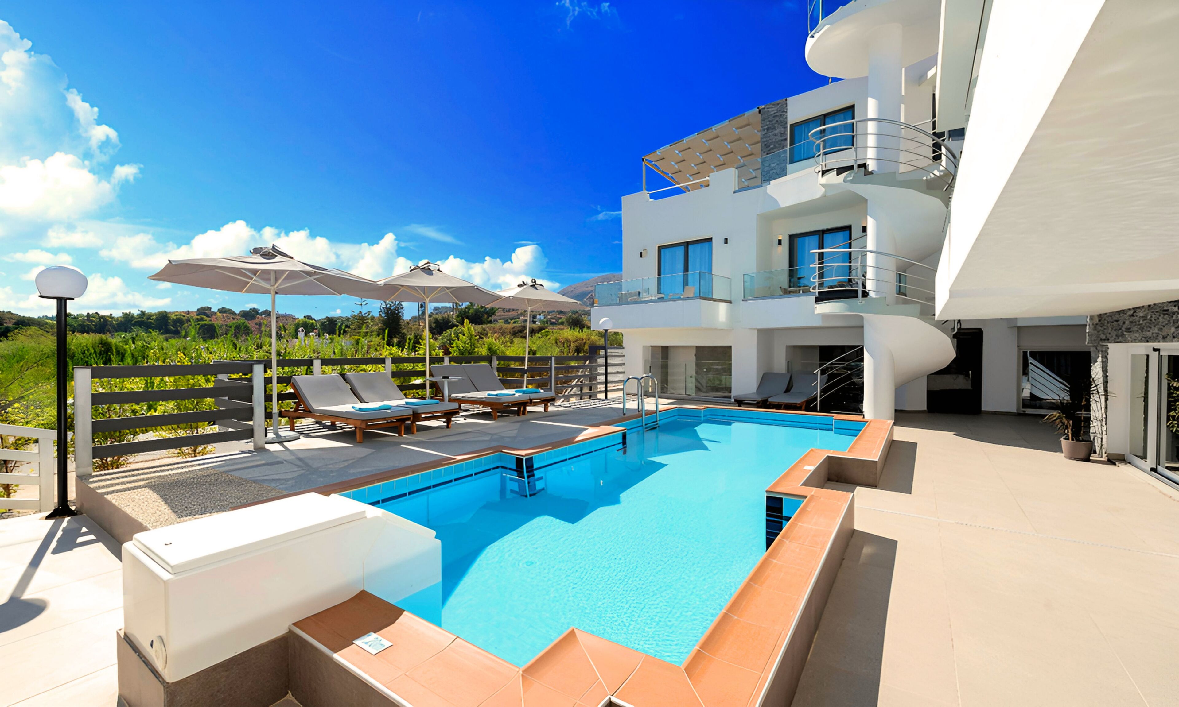 A modern hotel with a rooftop pool, sun loungers, and umbrellas.