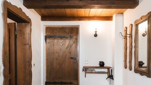 Un intérieur rustique avec une porte en bois, une étagère sur laquelle est posée une théière et des miroirs fixés au mur.