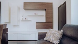 Ein modernes Wohnzimmer mit einer Couch, einem Zierkissen und eingebauten Holzbögen.